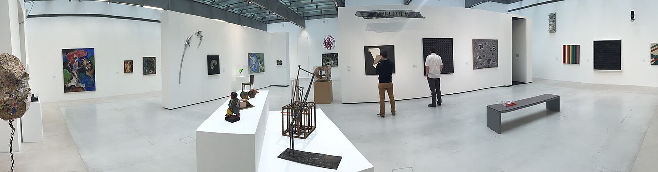 picture of an art exhibition, white room, two men staying in front of artworks